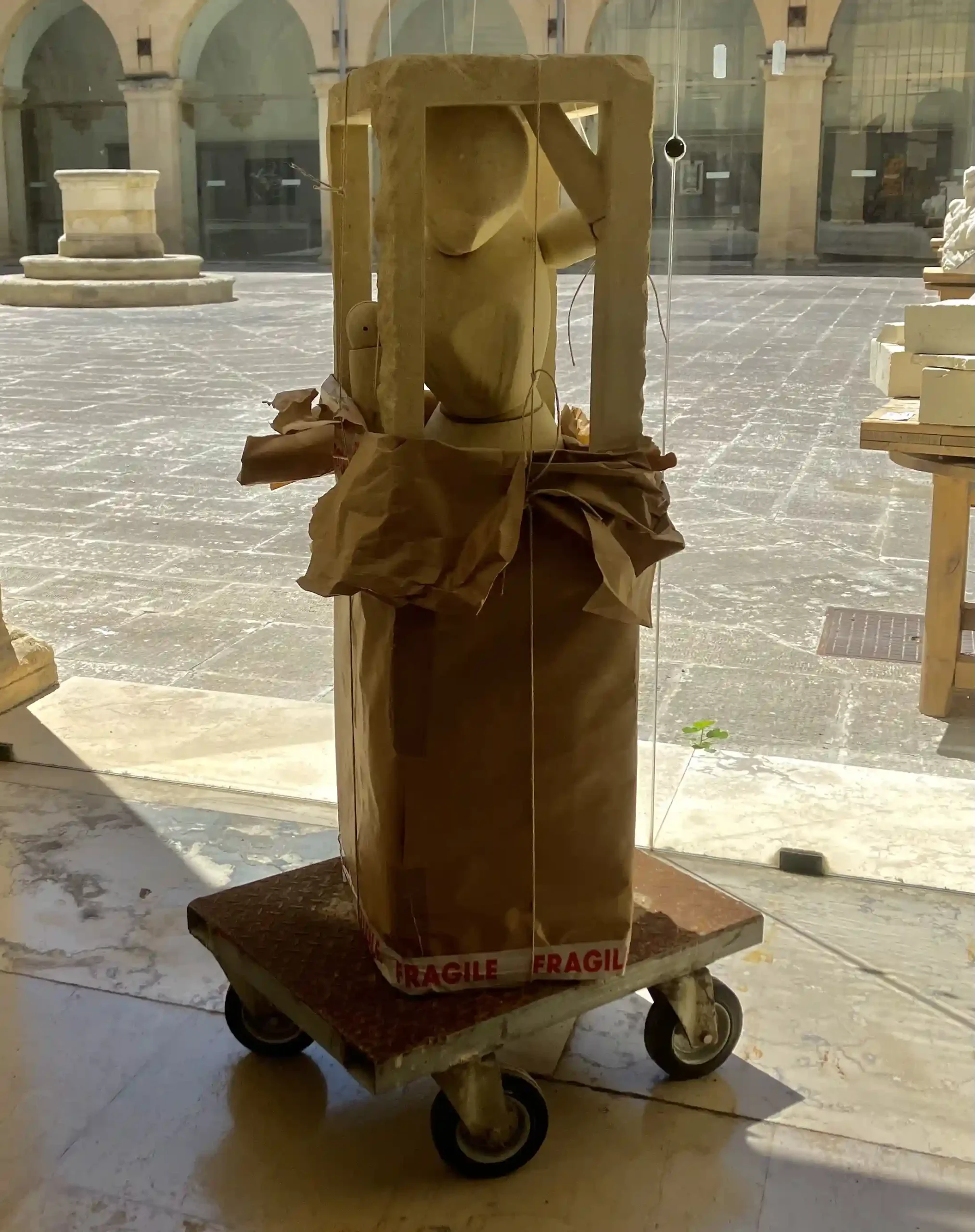 Andrea Buttazzo, Fragile, 2011, pietra, carta da imballaggio, spago, nastro adesivo, carrello in ferro, cm 133 x 60 x 45, collezione privata